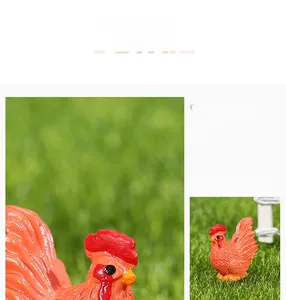 Close-up of orange resin rooster figurine with detailed feather texture on green grass
