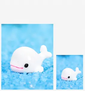 Vue détaillée d'une figurine de baleine blanche en résine sur du sable bleu de décor