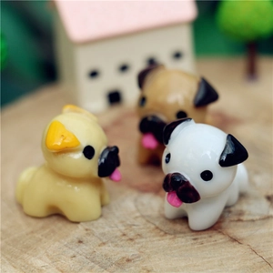 Close-up of three cute resin pug figurines in a miniature landscape with garden decor