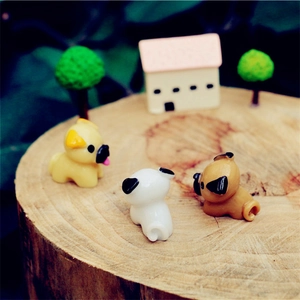 Three miniature resin pug figurines in assorted colors on wood for DIY garden decor