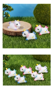 Close-up of cute resin unicorn miniatures with colorful stars on artificial lawn