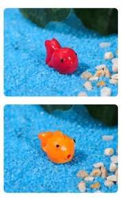 Macro detail of red and orange resin goldfish figurines in a miniature aquatic landscape