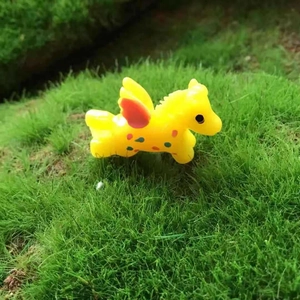 Cute yellow flying horse figurine with orange wings on green grass landscape decor