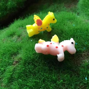 Macro detail of two colorful miniature unicorn figurines on artificial green moss