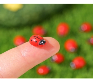 Macro detail of a tiny red wooden ladybug figurine held on a fingertip for scale