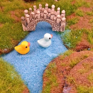 Miniature scene with two colorful ducks and stone arch bridge for moss micro landscape