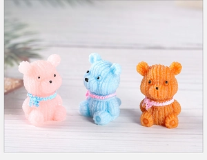 Three colorful resin bear miniatures with knitted texture and scarves on wood background
