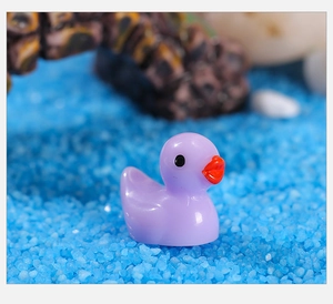 Gedetailleerd zicht op een paars hars eendenbeeldje op decoratief blauw zand