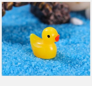 Macro-opname van een gele eend van hars op een levendige blauwe decoratieve zandachtergrond