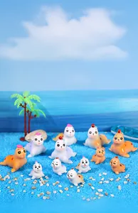 Miniature seal figurines in white and orange displayed on blue sand for micro landscapes