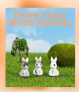 Three-color miniature resin rabbits in grey and white on a micro landscape lawn