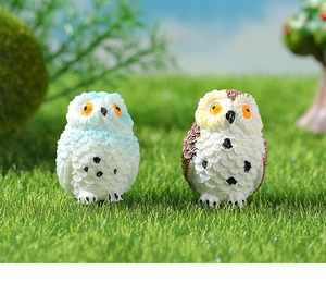 Macro detail of miniature resin owls with fine feather textures in a moss micro landscape