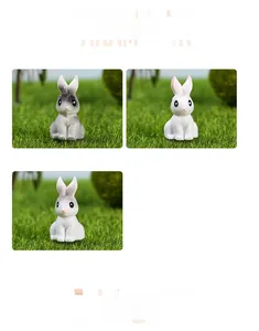 Detailed close-up of three miniature resin rabbits in different colors on green grass