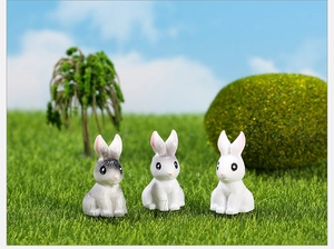Three miniature resin rabbit figurines on artificial grass for micro landscape decor