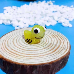 Macro shot of a cute green resin insect figurine on a rustic wooden slice for terrarium decor