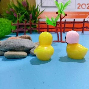 Miniatura di paesaggio con due anatre in resina gialla e decorazione con casco rosa