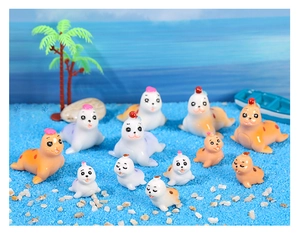 Miniature seal figurines set with trees and boat on blue sand micro landscape