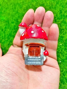 Nahaufnahme eines Miniatur-Pilzhauses aus Harz, das für den Größenvergleich gehalten wird