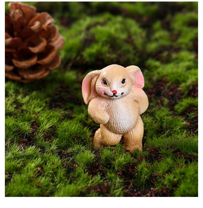 Close-up of miniature resin rabbit figurine with fur texture in a green moss setting