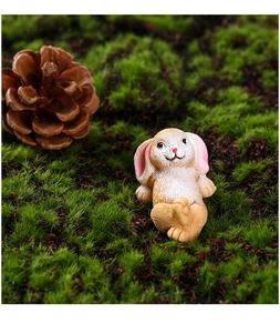 Close-up of a miniature resin rabbit with lifelike fur texture sitting on green moss