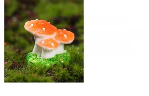 Macro shot of miniature red resin mushrooms with white dots on a green moss base