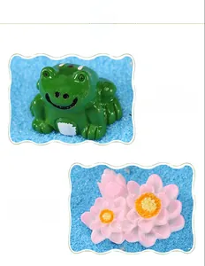 Détail d'une figurine de grenouille en résine avec lotus rose sur sable bleu décoratif
