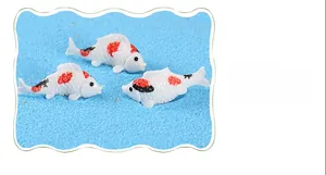 Vue macro détaillée de trois miniatures de carpes koï en résine avec taches rouges et noires
