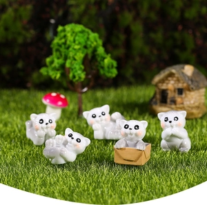 Miniatur-Katzenfiguren aus Harz in einem Feengarten mit Gras und Fliegenpilzhaus