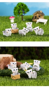 Nahaufnahme von Miniatur-Katzenfiguren aus Resinstoff mit kleinen Pappkartons