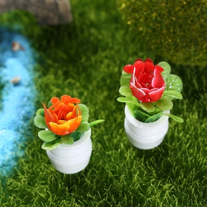Miniature dollhouse potted flower models with red and orange blossoms on green lawn