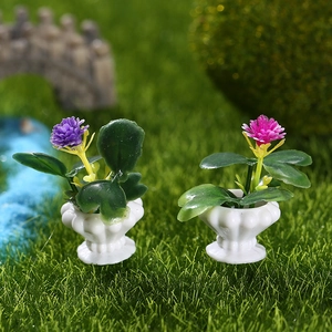 Miniatur-Puppenhaus-Topfpflanzen mit pinken und lila Blumen auf Moosrasen