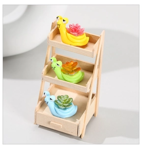 Three colorful resin snails with faux succulents displayed on a wooden shelf unit