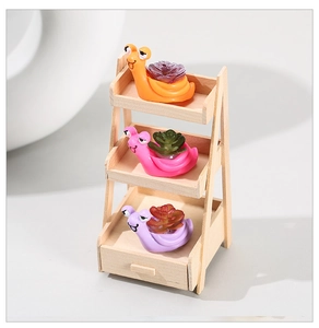 Three cute resin snail figurines with faux succulents on a tiered wooden display