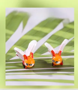 Two cartoon butterfly figurines in vibrant orange and white on green plant leaves