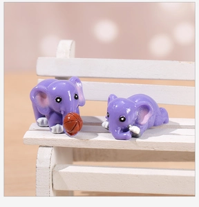 Detail of two miniature purple resin elephants on a tiny wooden bench for garden decor