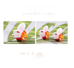 Miniature resin insect figure with orange body and dotted wings on green leaves