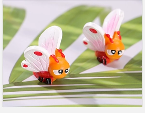 Detailed macro view of cute cartoon insect resin figurines on a green leaf prop