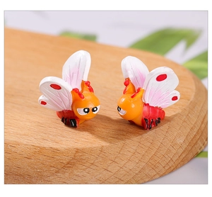 Macro shot of cute resin bee and butterfly miniatures on a wooden surface for micro landscapes