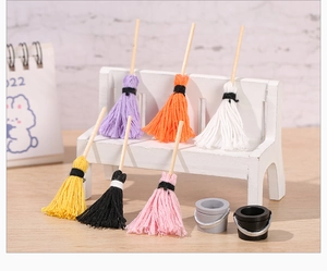 Miniature colorful mops and buckets displayed on a tiny wooden bench for dollhouses