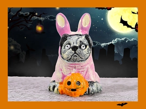 Close-up of a resin pug dog in a pink bunny costume holding an orange Halloween pumpkin