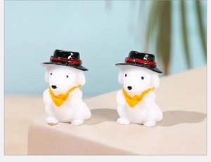 Detail of two white resin puppy figurines with black hats and yellow scarves for DIY decor