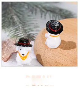 Detail view of two miniature resin puppy figurines with black hats on a wooden base