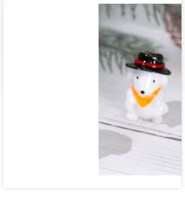 Close-up of a miniature resin puppy figurine with a black hat and orange scarf detail