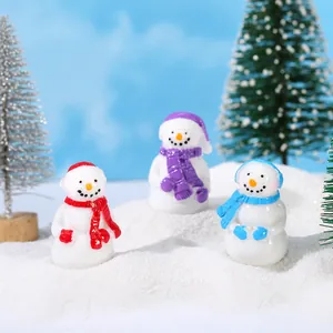 Detailed view of three resin Christmas snowman figurines on artificial snow with a tree