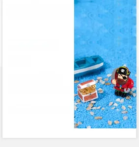 Miniature pirate resin set featuring gold treasure chest and small blue boat on blue sand