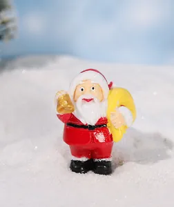 Miniature resin Santa Claus figurine with golden bell on a snowy winter background