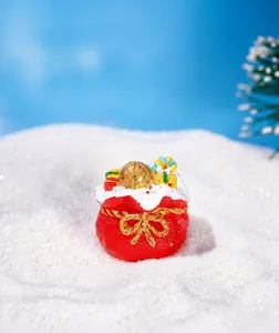 Close-up of resin Christmas gift bag miniature with gold bow on snow background