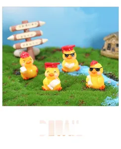 Detailed view of four resin graduation ducks in mini landscape with school caps and scrolls