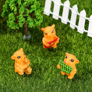 Three orange resin hamster figurines playing musical instruments in a micro garden setting