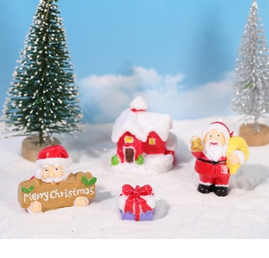 Miniature Christmas set with Santa figures and red cottage on faux snow background